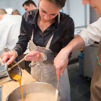 Cucinaria Kochschule A Kochkurs in der Cucinaria Kochschule. Zwei Personen über einen Topf gebeugt.