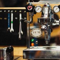 Cucinaria Werkstatt Siebträgermaschine in Chrom. Im Hintergrund hängt Werkzeug.