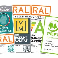 Es sind vier Logos von Qualitätssiegeln zu sehen. Von links nach rechts: RAL Made in Germany, RAL das Goldene M, RAL Emissionsklasse A, PEFC